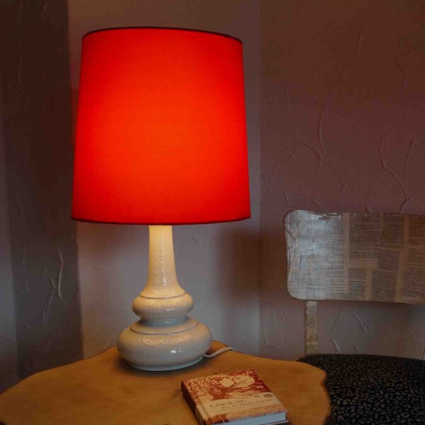 Eine große Tischlampe mit auffälligem, rotem Schirm und Wallendorfer Porzellan-Fuß in Weiß